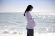 A pregnant woman walking on the beach, smiling