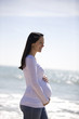 A pregnant woman walking on the beach, smiling