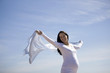 A pregnant woman holding a scarf into the wind