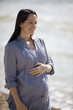 Portrait of a pregnant woman standing on the beach, smiling