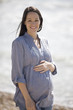 Portrait of a pregnant woman standing on the beach, smiling