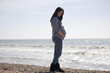 A pregnant woman standing on the beach