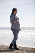 A pregnant woman standing on the beach, smiling