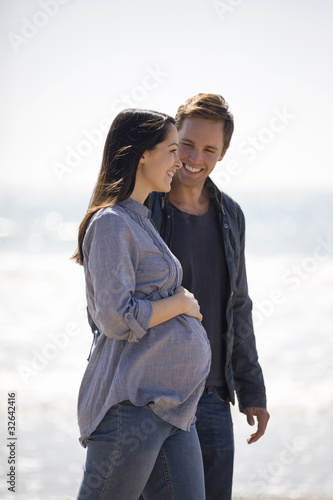 Photo: A pregnant woman and her partner walking on the beach A pregnant woman and her partner walking on the beach