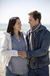 A pregnant woman and her partner standing on the beach