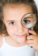 little girl looking through a magnifying glass