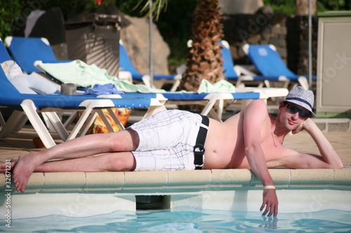 Foto: Porträt einer schönen jungen Mann liggen am Rand eines Pools Porträt einer schönen jungen Mann liggen am Rand eines Pools