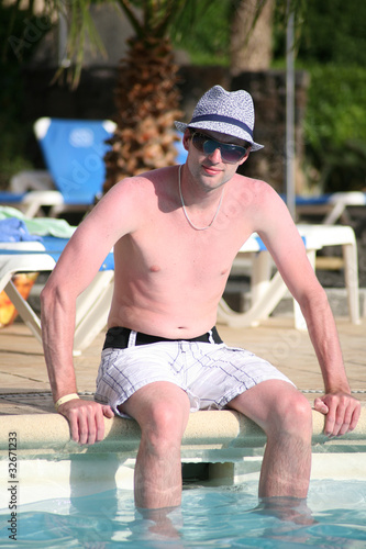 Foto: Porträt einer schönen jungen Mann sitzen am Rand eines Pools Porträt einer schönen jungen Mann sitzen am Rand eines Pools