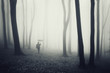 man with umbrella walking in a dark forest with fog