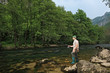 Young fisherman fishing on a river with trees in the background Young fisherman fishing on a river with trees in the background