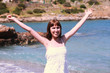 Young smiling girl on the gravel beach in white dress