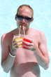 Portrait of a young man in the pool with a cocktails