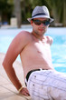handsome young man sitting on the edge of a pool