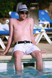 Portrait of a handsome young man sitting on the edge of a pool