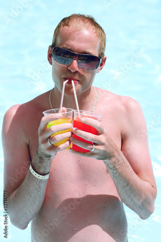 Foto: Portrait of a young man in the pool with a cocktails Portrait of a young man in the pool with a cocktails