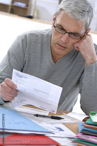Photo: Particulier penché sur les factures et charges Particulier penché sur les factures et charges