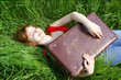Young woman with suitcase on grass