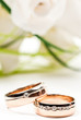 Pair of golden wedding rings with rose bouquet. Macro photo