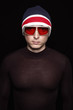 Young man in red and blue hat with sunglasses on black