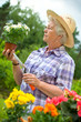 Senior woman with a pot of flowers in her garden