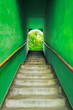 Old grungy stairs with handrails on green wall