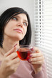 Thoughtful brunette girl drinking tea at the window