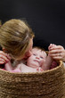 Mama kuesst Baby im Waeschekorb