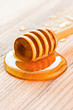 Drops of fresh honey and dipper on wooden table