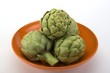 Photo: Raw artichokes in an orange ceramic bowl Raw artichokes in an orange ceramic bowl