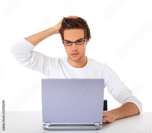Photo: Junger Mann sitzt ratlos vor seinem Computer Junger Mann sitzt ratlos vor seinem Computer