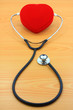 red heart and stethoscope on wood background