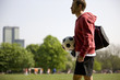 A young man carrying a football and a sports bag
