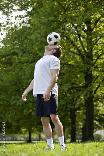 Foto: A young man balancing a football on his forehead A young man balancing a football on his forehead