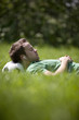 A young man lying on the grass, head resting on a football