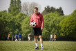 A young man standing in the park, holding a football