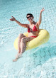 Junge Frau sitzt im Schwimmreife und  spritzt mit Wasser