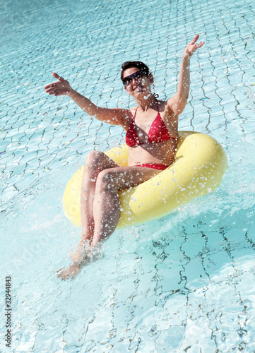 Foto: Junge Frau sitzt im Schwimmreife und spritzt mit Wasser Junge Frau sitzt im Schwimmreife und spritzt mit Wasser