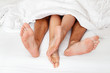 Feet of one couple in bed.