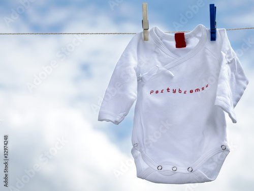 Photo: Little babygro on a clothesline in front of blue sky Little babygro on a clothesline in front of blue sky