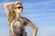 beautiful girl in sunglasses on background blue sky
