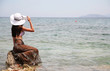 young woman with long hair sitting on big stone in water