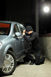 Thief wearing a robbery mask trying to steal a car