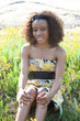 Lovely black woman sitting outside in some yellow dasies