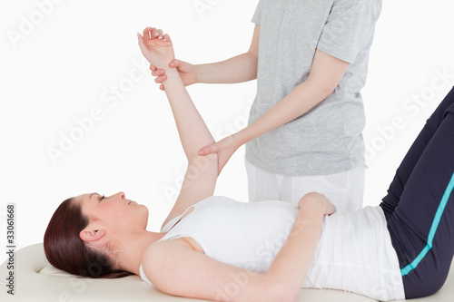 Photo: Sportswoman having her arm stretched by a masseuse Sportswoman having her arm stretched by a masseuse