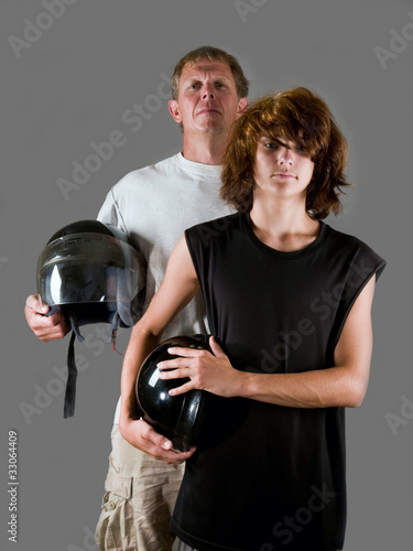 Foto: Bikers together - father and teen son holding motorcycle helmets Bikers together - father and teen son holding motorcycle helmets
