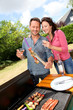 Happy couple cooking meat on barbecue grill