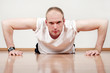 Young strong handsome man doing push-ups in sport center