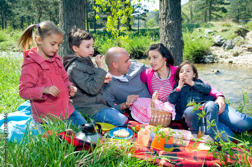 Foto: Young family having picnic by the river Young family having picnic by the river