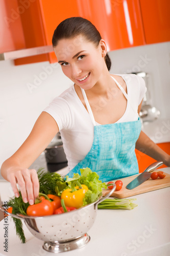 Photo: Beautiful young woman cooking in the kitchen Beautiful young woman cooking in the kitchen