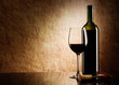 green bottle with red wine and glass and cork with a corkscrew